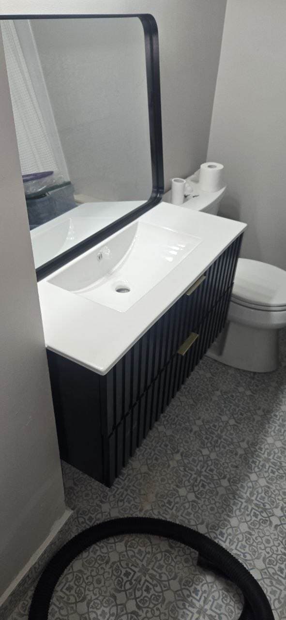 Black bathroom vanity installed over patterned tile floor by BAX