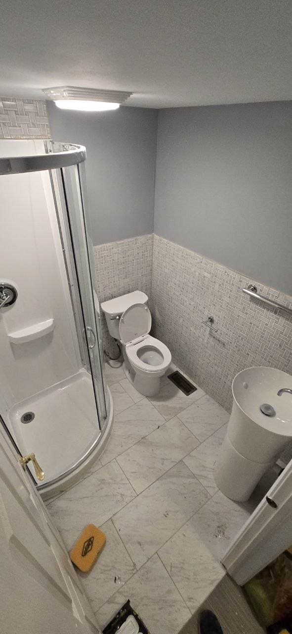 Bathroom remodel with marble-look floor tile and wall tile wainscot by BAX