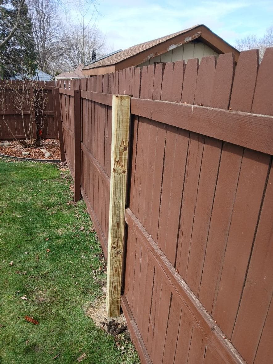 New wood fence post installed beside an existing backyard fence by BAX