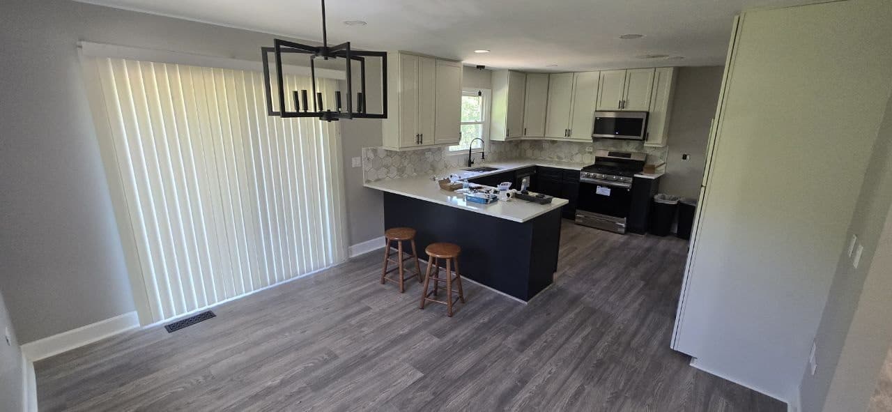 Kitchen and dining area with finished gray laminate plank flooring by BAX